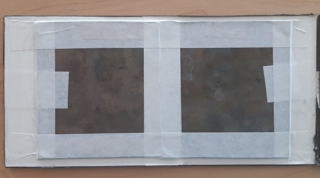 Cette image montre la moitié de l'intérieur du paquet du daguerréotype stéréoscopique. Il est composé du verre églomisé (peint du côté interne), qui est recouvert d'une carte en papier blanc. Les deux plaques de daguerréotype sont maintenues sur leurs bords par un ruban adhésif en papier blanc.