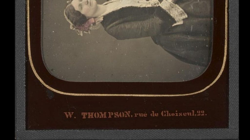 This image is a picture of a stereo-daguerreotype by W. Thompson, from the Bibliothèque national de France collection, depicting a half-portrait of a woman. This image shows a detail of the reverse-painted signature.