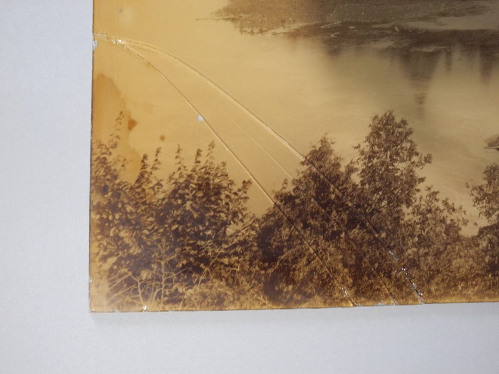 Documentation préalable au traitement de conservation-restauration d'un tirage albuminé monté sous verre. Détail du coin inférieur gauche, recto.