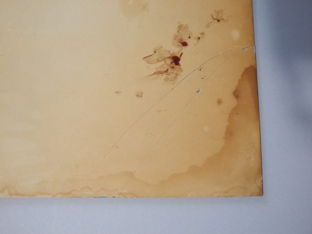 Documentation préalable au traitement de conservation-restauration d'un tirage albuminé monté sous verre. Détail du coin inférieur gauche, verso.