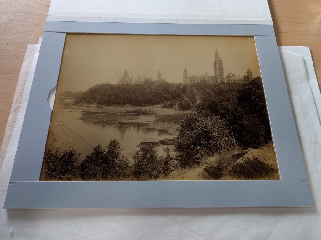 Après traitement de conservation d'une photographie du bâtiment original du Parlement canadien. Écrin sur mesure créé pour protéger et soutenir le tirage sur papier albuminé monté sous verre, dont le coin inférieur gauche a été réparé.
